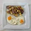 Eggs with potatoes on the pan and village sausage